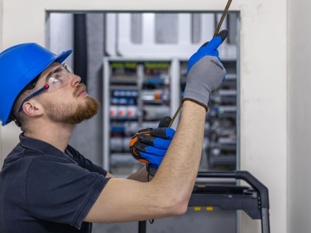 Electrician installing laying electrical cables on elevator