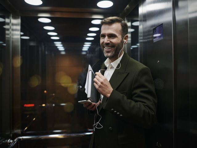 Portrait of smiling businessman listening to music in elevator