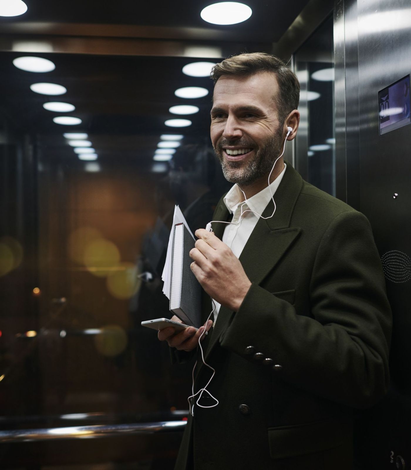 Portrait of smiling businessman listening to music in elevator
